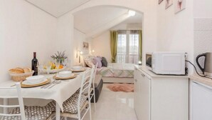 Un espacio habitable compacto con comedor, kitchenette y cama.