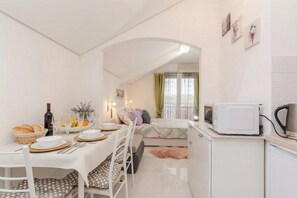 Ein kompakter Wohnbereich mit Essplatz, Küchenzeile und einem Bett.