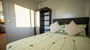 A bedroom with a bed, pillows, a wardrobe, and a door.