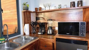 A compact kitchen with a sink, coffee maker, blender, microwave, and a dishwasher.