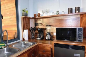 Une cuisine compacte équipée d’un évier, d’une machine à café, d’un mixeur, d’un four à micro-ondes et d’un lave-vaisselle.