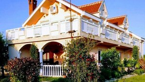 Ein zweistöckiges Haus mit Balkon, Schornstein und einer Veranda mit Geländer.