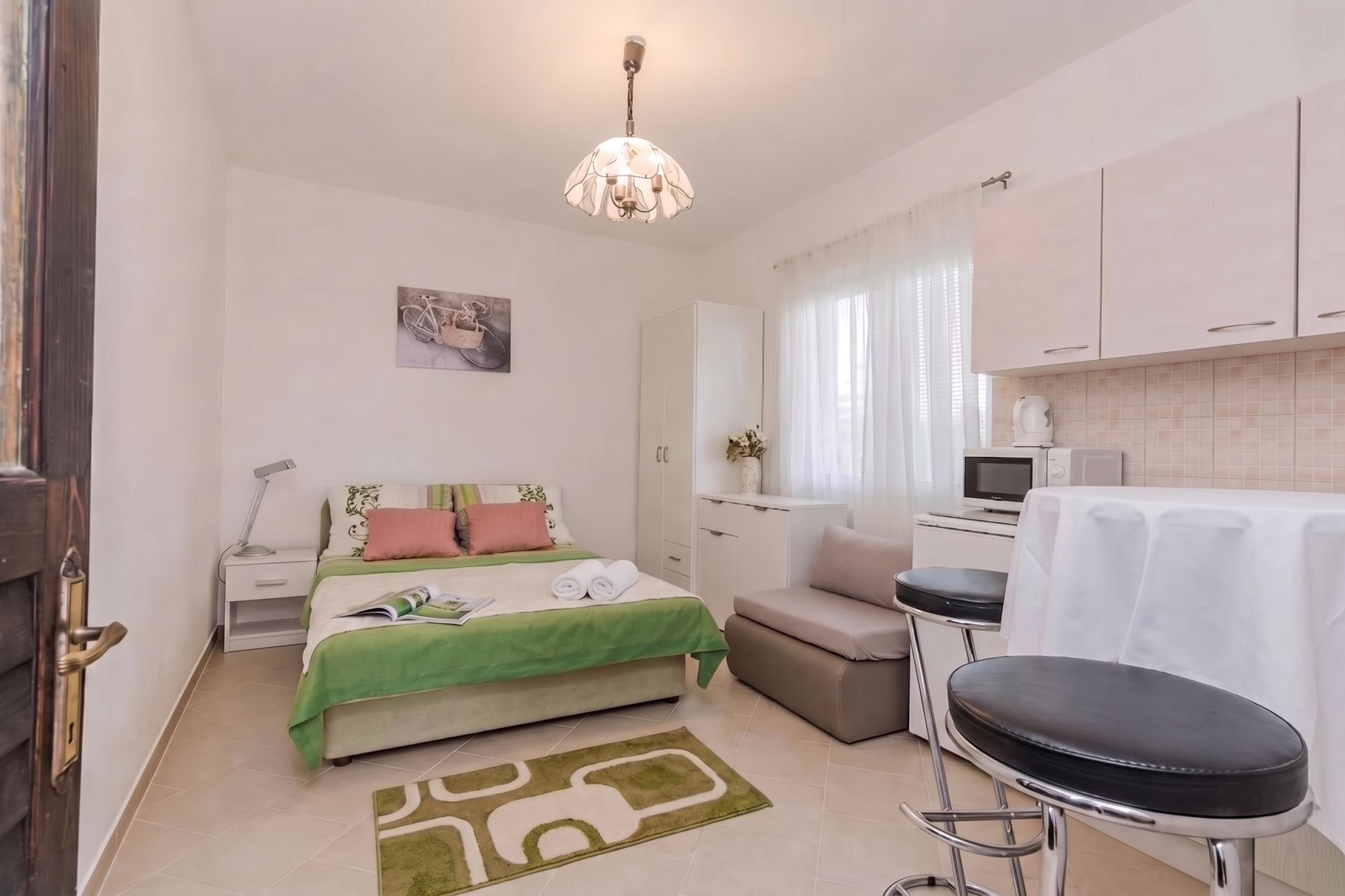 Ein kleines Hotelzimmer mit Bett, einer Küchenzeile, einem Essbereich und einem Badezimmer.