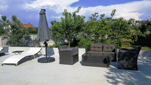 Ein Außenbereich mit Lounge-Möbeln, einer Sitzecke und einem Sonnenschirm.