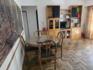 A dining area with a round table and chairs, wooden cabinets with glass doors, and a painting on the wall. - Apartment. 2 bdrm. w / balcony V. Crespo (Villa Crespo)