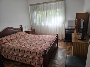A bedroom with a wooden bed, a desk with a computer, a TV, and a window with sheer curtains. - Apartment. 2 bdrm. w / balcony V. Crespo (Villa Crespo)