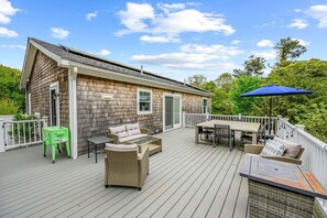 Eine Holzterrasse mit Gartenmöbeln, einem Tisch und einem blauen Sonnenschirm.
