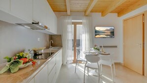 Uma cozinha moderna com armários brancos, um exaustor de aço inoxidável e uma área de jantar com mesa e cadeiras.