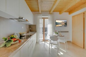 Eine moderne Küche mit weißen Schränken, einer Edelstahl-Dunstabzugshaube und einem Essbereich mit Tisch und Stühlen.