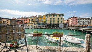 Um canal com barcos atracados, edifícios ao longo da água e uma ponte ao fundo.