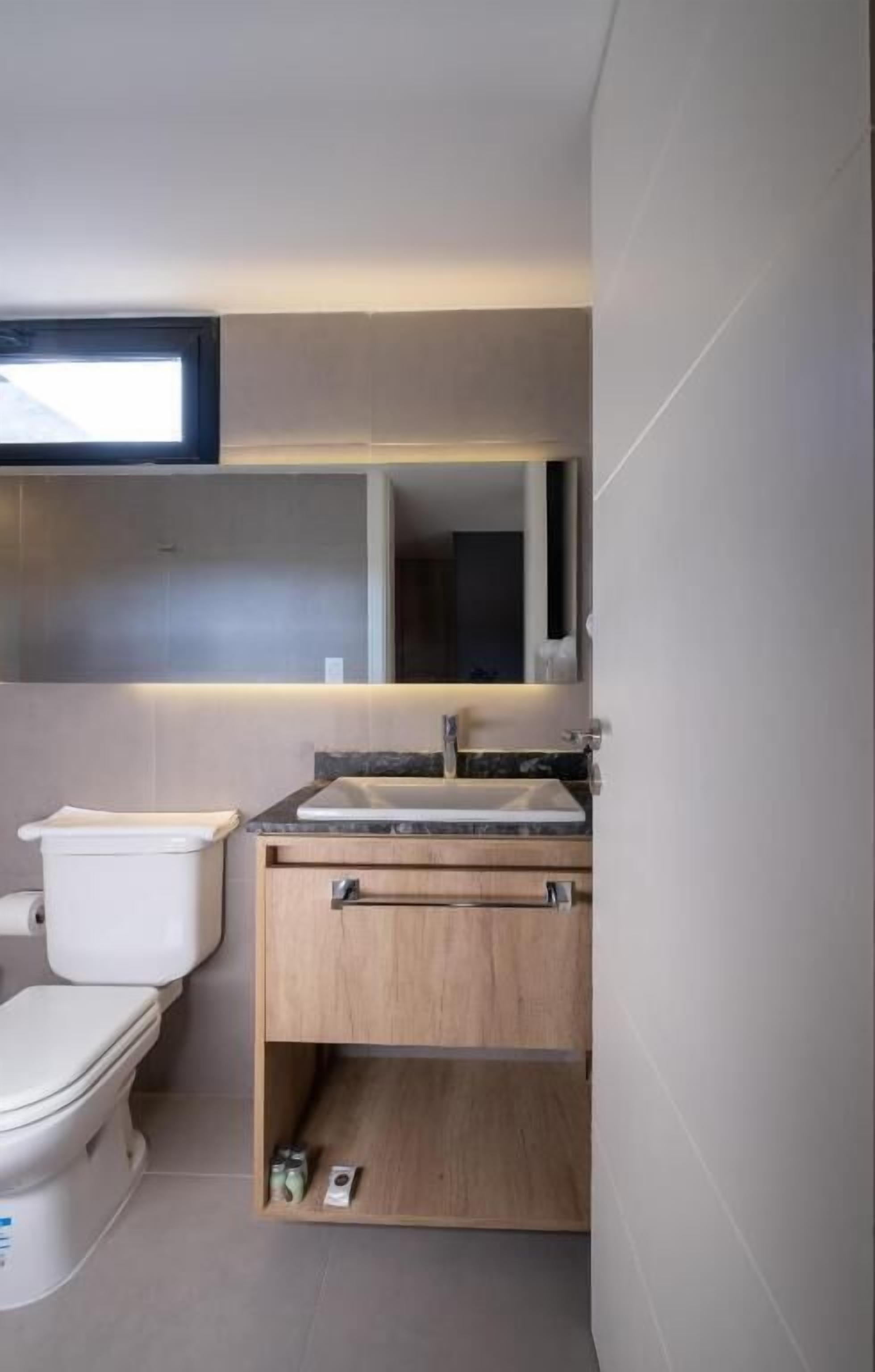 A compact bathroom with a toilet, sink, and mirror.