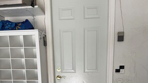 A white door with a small step leading up to it, a white metal gate with a grid pattern, and a wall with electrical outlets. - Vancouver in Style - Newly listed renovated home in Delta's Sunshine Hills (Delta)