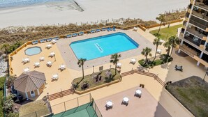 Ein Poolbereich mit Liegestühlen und einem kleinen Gebäude mit Blick auf einen Strand.