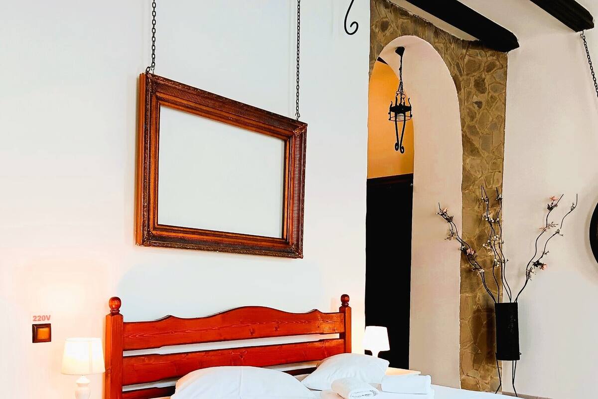 A neatly made bed with white linens, a wooden headboard, and a bedside table with a lamp.