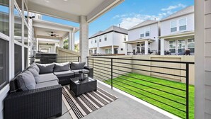 Eine überdachte Terrasse mit einer Couch, einem Couchtisch und einem Deckenventilator.