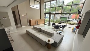 A modern interior with a sectional sofa, a small round table, and a dining area with chairs. - Dommy (São Paulo)