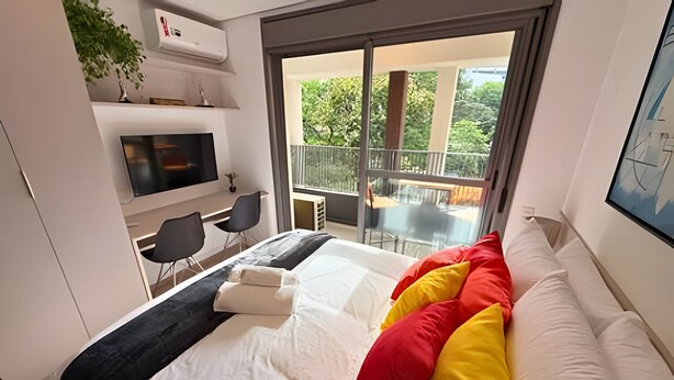 A modern hotel room with a bed, a TV, a balcony, and a dining area. - Dommy (São Paulo)
