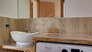Ein Badezimmer mit Waschbecken, Holzschrank, Spiegel und Waschmaschine.