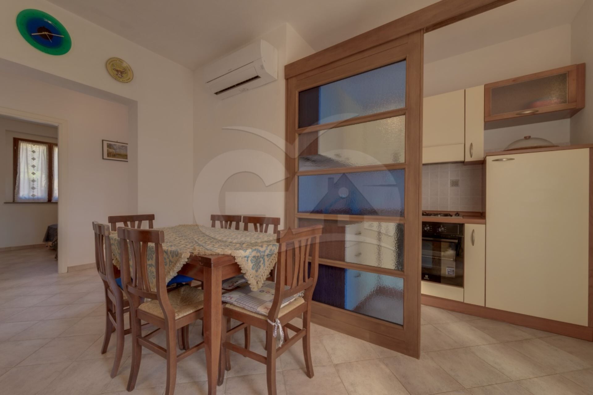 A dining area with a table and chairs, a kitchen with cabinets and appliances, and a large window with a view.