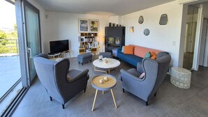 A modern living room with a sofa, two armchairs, a coffee table, a TV, a bookshelf, and a fireplace. - Beautiful villa, sea view, swimming pool, WIFI (ST MANDRIER SUR MER)
