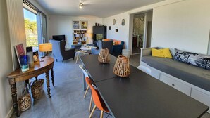 A modern living room with a sofa, dining table, chairs, and a TV. - Beautiful villa, sea view, swimming pool, WIFI (ST MANDRIER SUR MER)