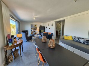 Ein modernes Wohnzimmer mit einer Couch, einem Esstisch, Stühlen und einem Fernseher.