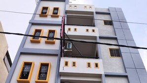 A multi-story building with balconies, air conditioning units, and a brown garage door. - Guru Mauli Yatri Nivas (Shirol)