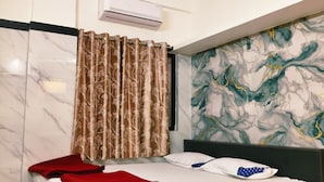 A modern bedroom with a bed, curtains, an air conditioning unit, and a marble-patterned wall. - Guru Mauli Yatri Nivas (Shirol)
