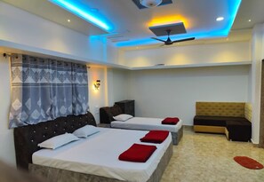 Ein Hotelzimmer mit zwei Betten, einem Deckenventilator, einer Couch und einem roten Teppich.