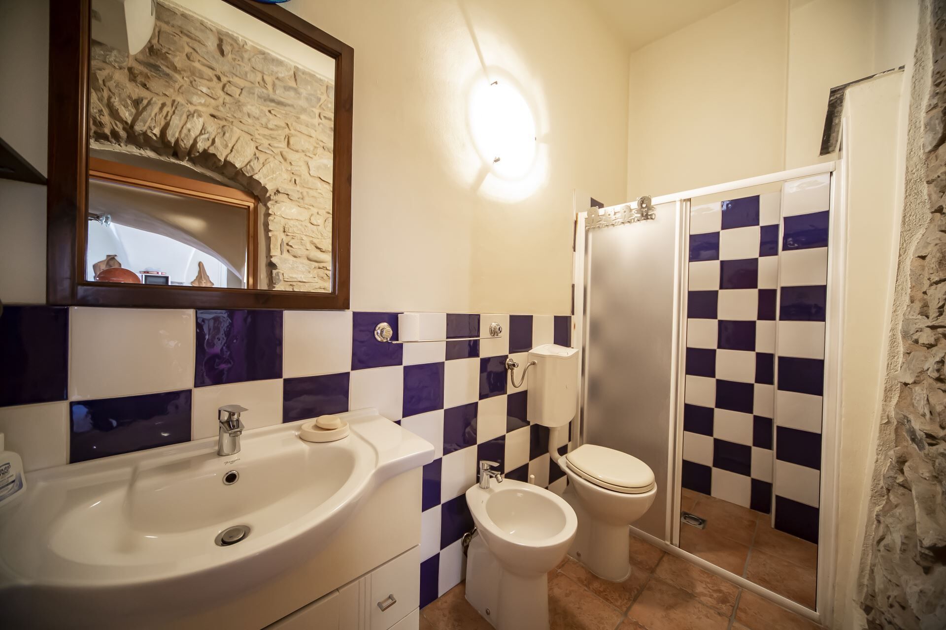 A bathroom with a sink, toilet, bidet, and a shower area.