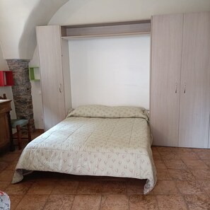 Ein Schlafzimmer mit einem Bett, einem Kleiderschrank, einem Schreibtisch und einem Sessel.