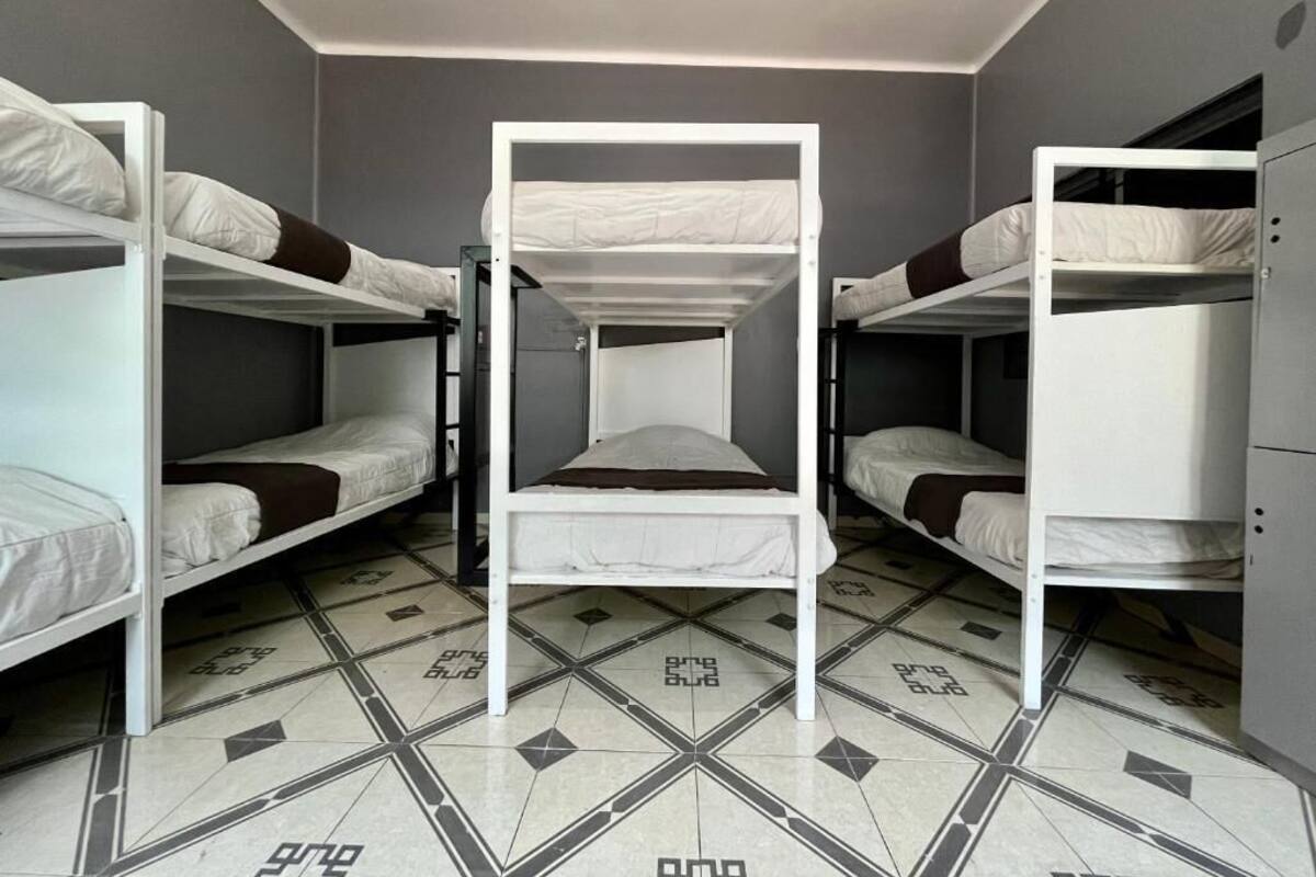 A dormitory room with bunk beds, a tiled floor, and a wardrobe.