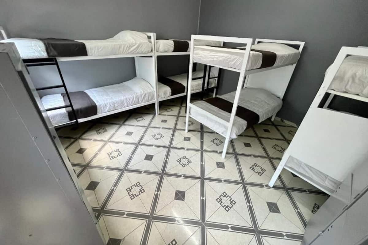 A room with bunk beds, a tiled floor, and a grey wall.