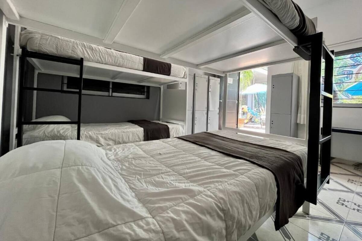 A compact room with bunk beds, a sliding door to a balcony, and a small kitchenette.