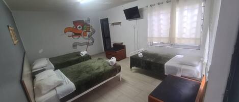 A room with two beds, a TV, a window with curtains, and a wall painting.