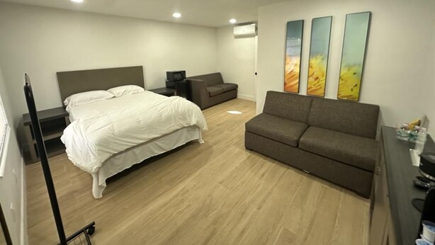 A bedroom with a bed, a sofa, a desk, and three wall-mounted artworks. - Sunshine Inn (Holiday)