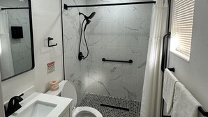 A modern bathroom with a shower, toilet, sink, and a mirror. - Sunshine Inn (Holiday)
