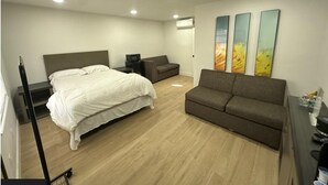 A hotel room with a bed, a sofa, a desk, and three paintings on the wall. - Sunshine Inn (Holiday)