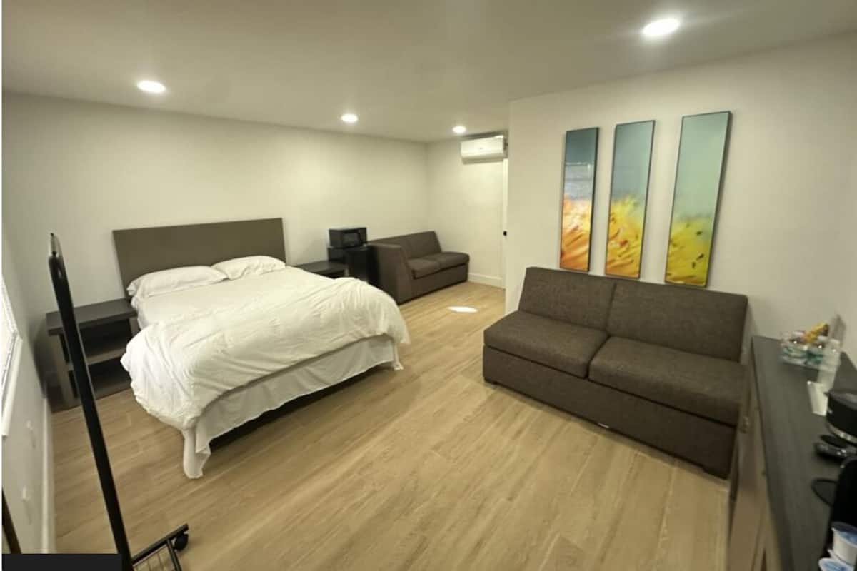 Una camera d'albergo con un letto, un divano, una scrivania e tre quadri appesi al muro.