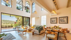 A spacious living area with a large window, a dining table set for four, and a cozy seating arrangement.