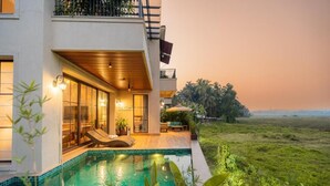 A modern house with a swimming pool, large windows, and a view of the sea.