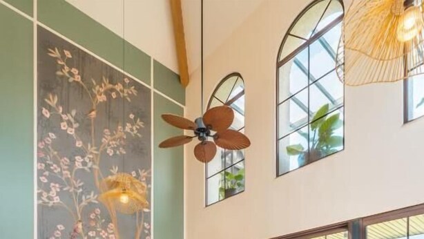 A spacious living room with a large TV, comfortable seating, and large windows offering a view of the outdoors.
