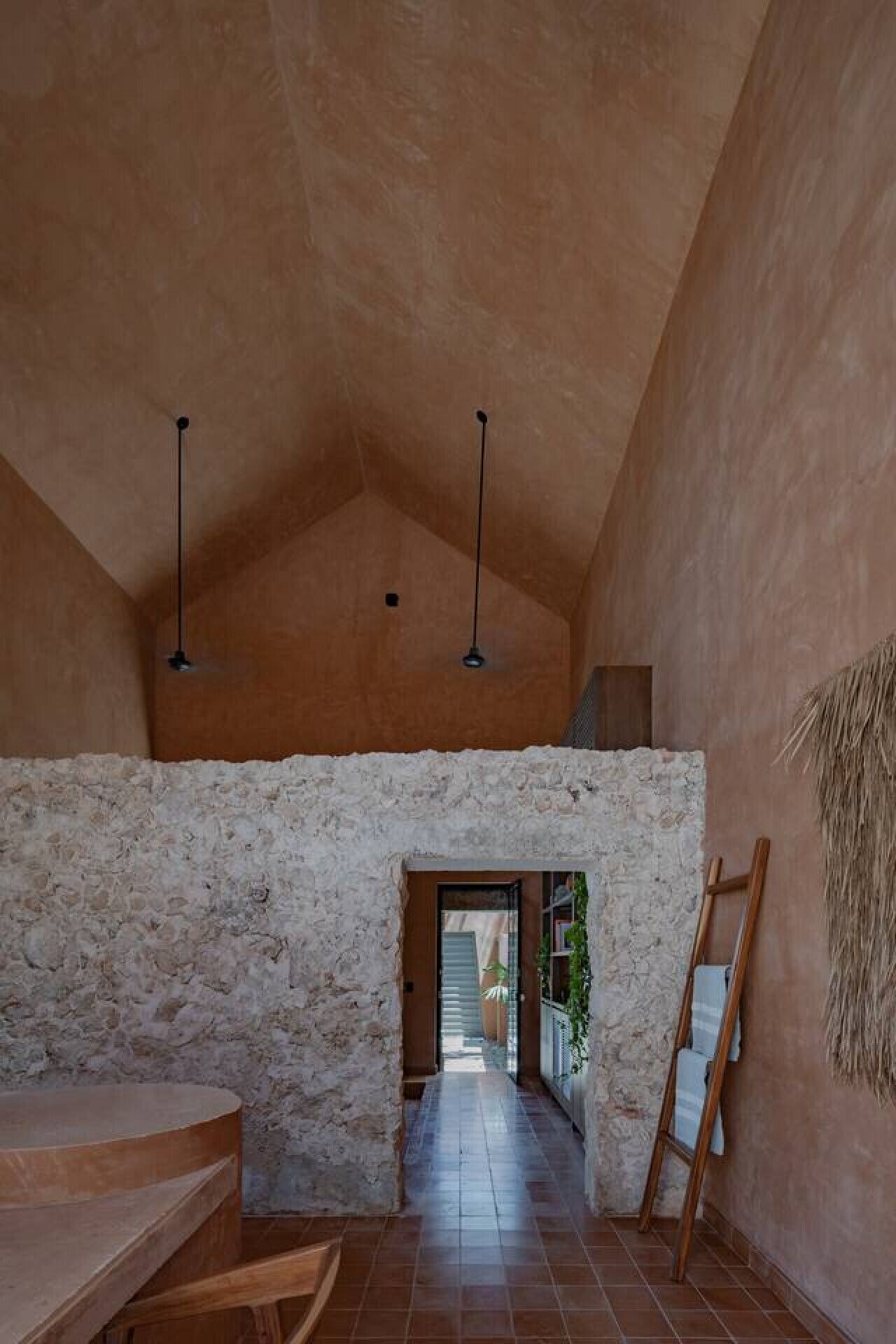 Un intérieur spacieux avec un plafond haut, un mur en pierre et un plancher en bois.