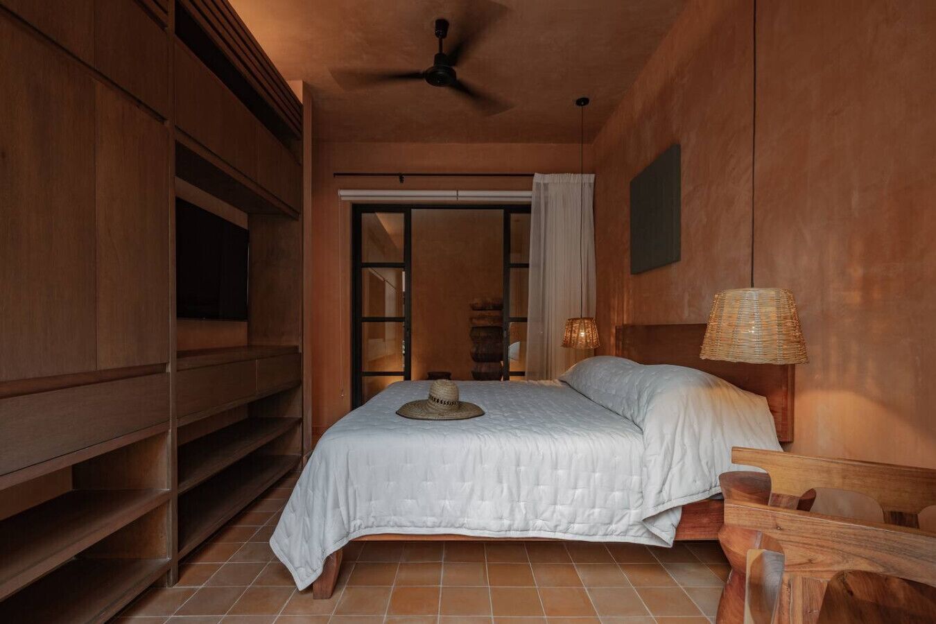 Une chambre à coucher comprenant un lit, un ventilateur de plafond, une table de chevet, une lampe et une armoire.