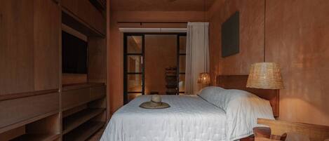 Une chambre à coucher comprenant un lit, un ventilateur de plafond, une table de chevet, une lampe et une armoire.