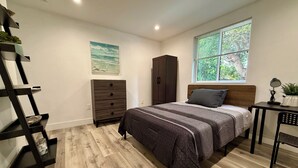 A bedroom with a bed, a dresser, a desk, a window with a view, and a painting on the wall. - USC Private Suite & Bath/Long-Term/Utilities, Wi-Fi & Laundry Incl. 4m to campus (Los Angeles)