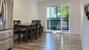 A modern kitchen with a built-in refrigerator, wooden dining table with chairs, and a large sliding glass door leading to a balcony. - USC Private Suite & Bath/Long-Term/Utilities, Wi-Fi & Laundry Incl. 4m to campus (Los Angeles)