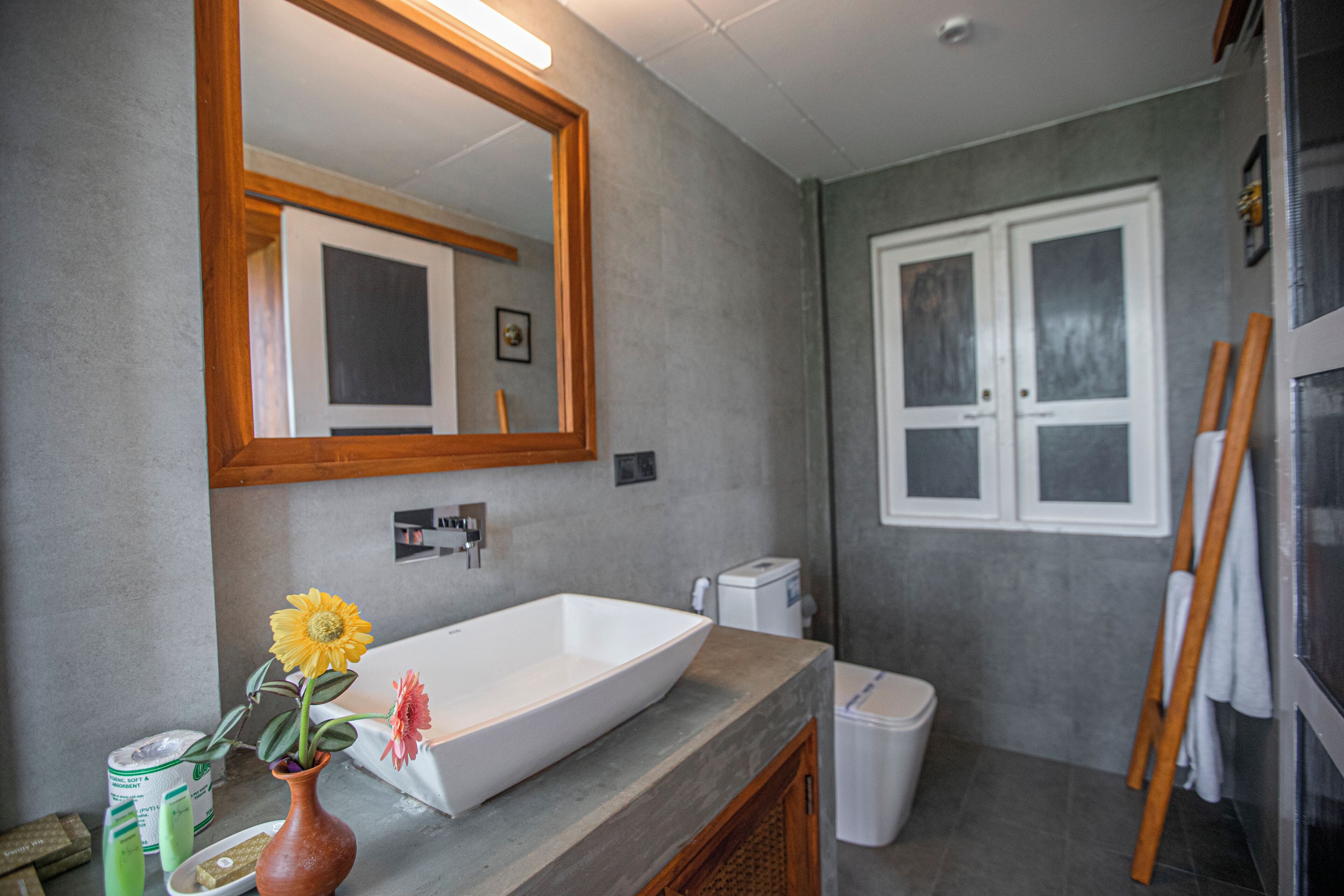 A bathroom with a large mirror, a white sink, a towel rack, and a window.