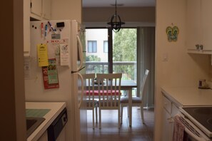 Eine Küche mit weißen Schränken, einem Kühlschrank und einem Essbereich mit Tisch und Stühlen.