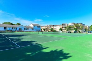 Ein Tennisplatz mit Netz, umgeben von mehrstöckigen Gebäuden.